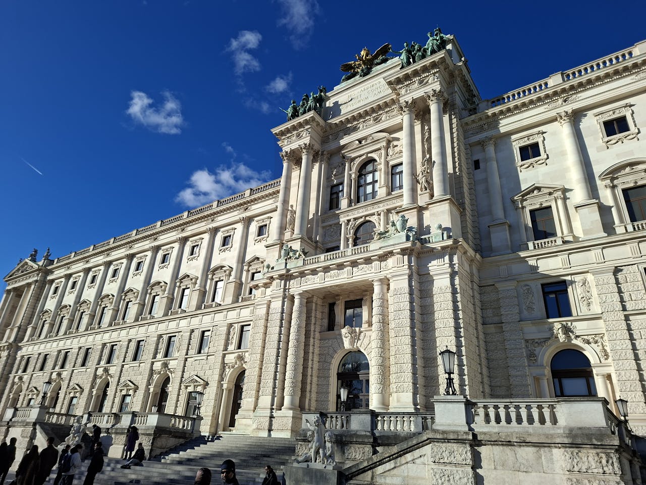 Stunning view of Vienna's Hofburg Palace with people gathered outside on a sunny day.